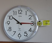 わいわいランドの時計の画像です。分針に赤いテープ、予定時刻の数字の隣にキャラクターの絵が付いています。
